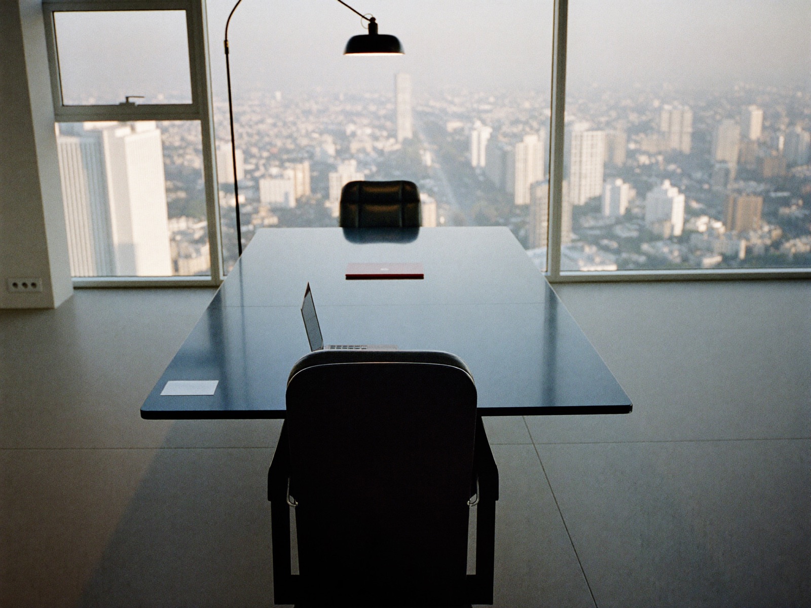 Sala de juntas corporativa vacía al amanecer con una silla girada hacia la ventana