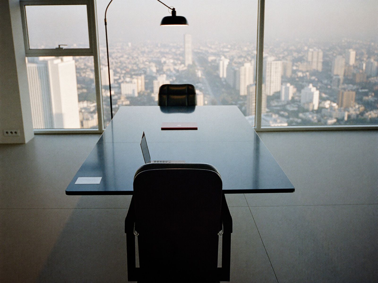 Sala de juntas corporativa vacía al amanecer con una silla girada hacia la ventana
